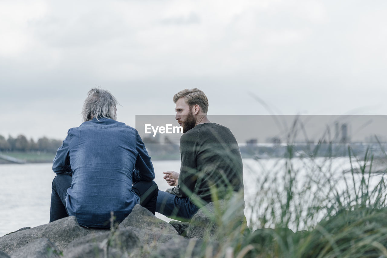 Father and son meeting at rhine river in autmn, talking together