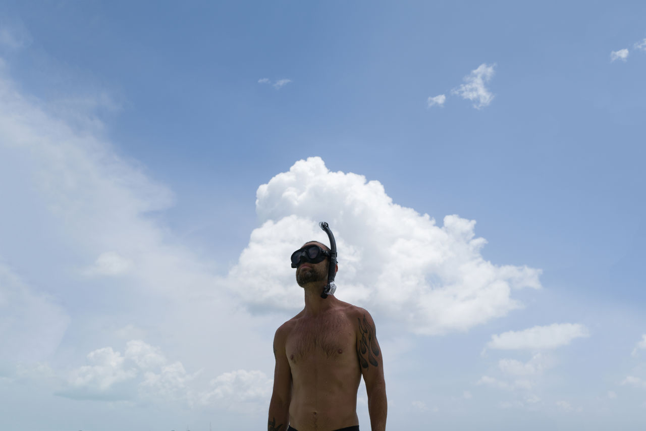 Man wearing snorkeling mask against cloudy sky