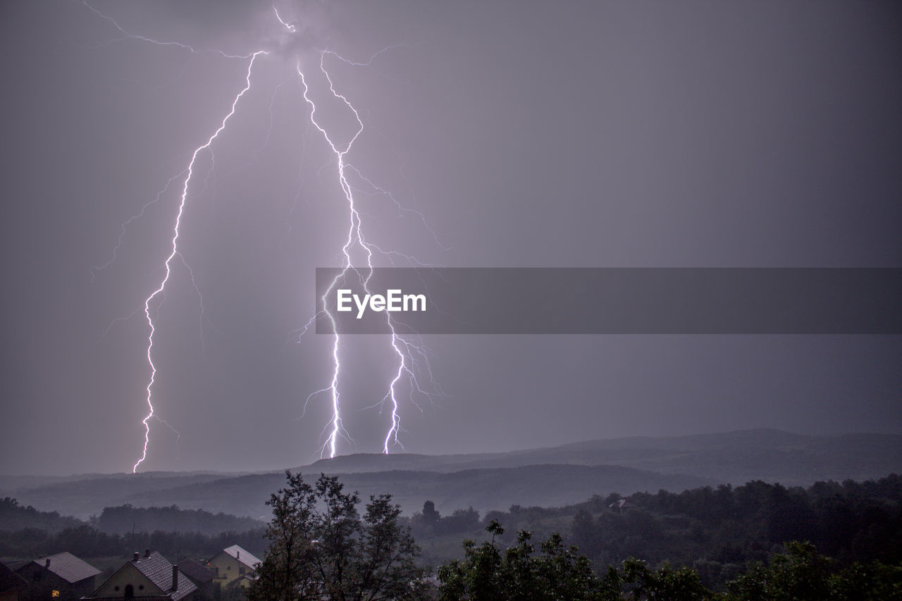 Lightning over mountains against sky at night