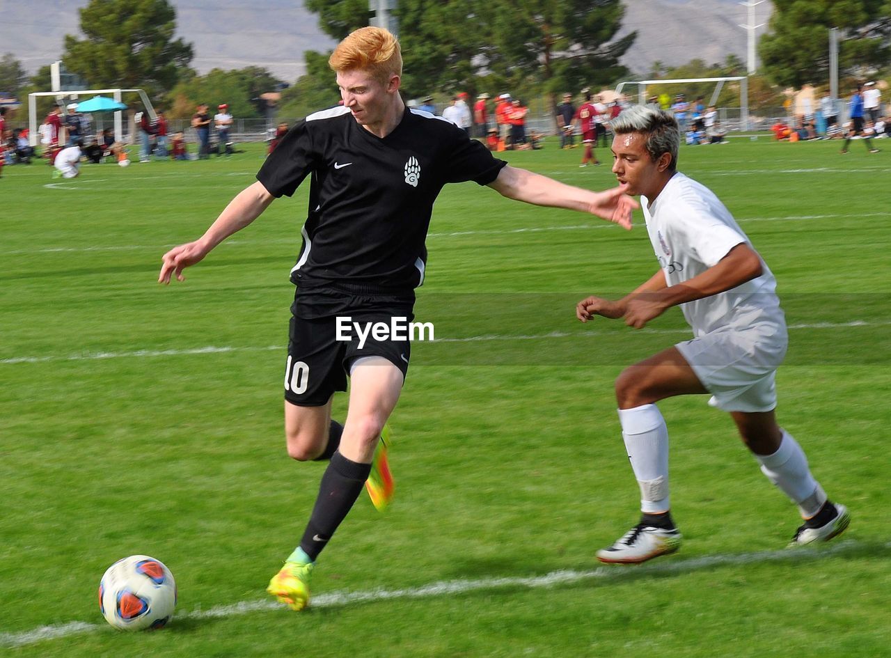 FULL LENGTH OF BOYS PLAYING SOCCER ON FIELD