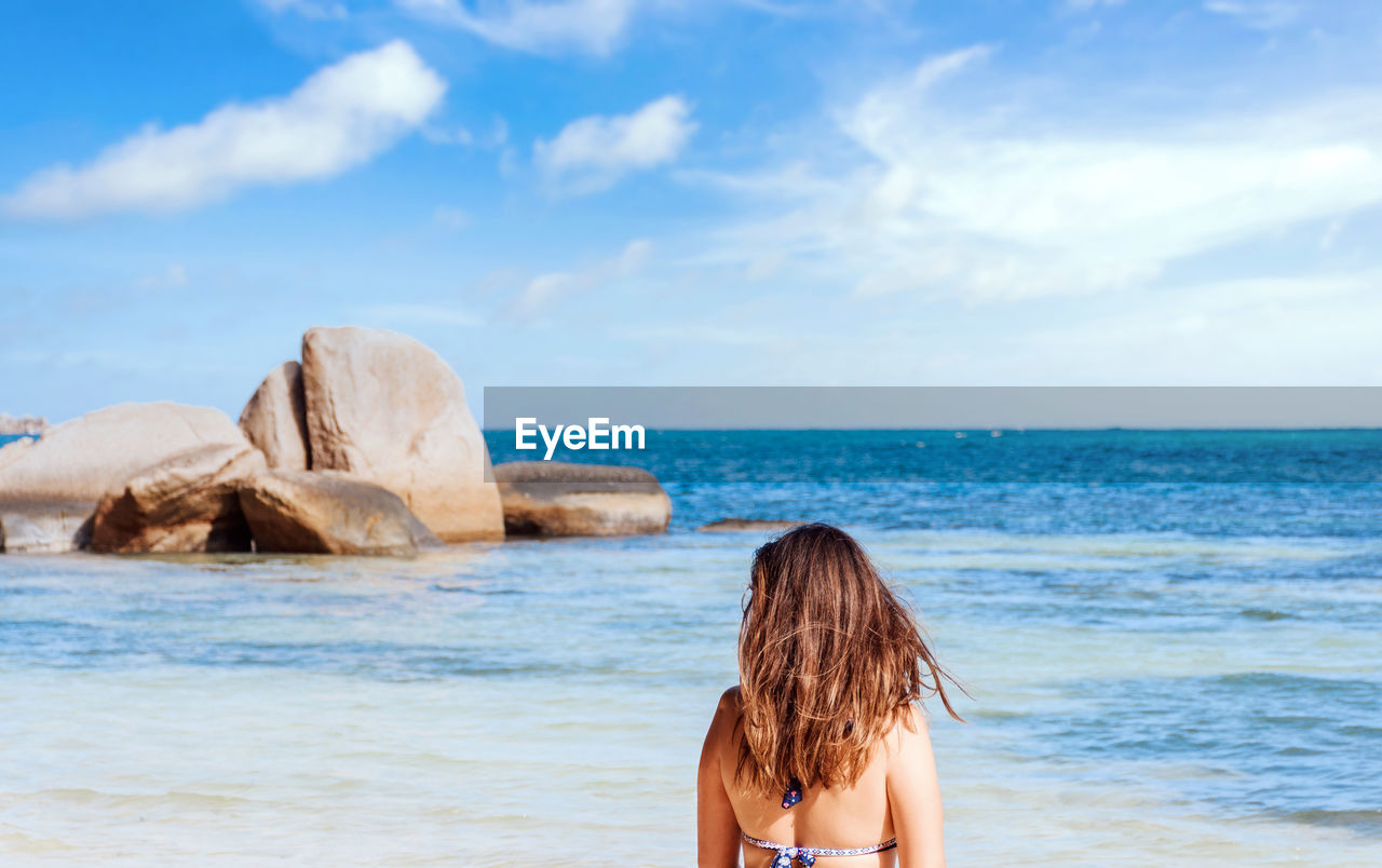 Woman from behind on tropical beach, blue, horizon, one person, hair.