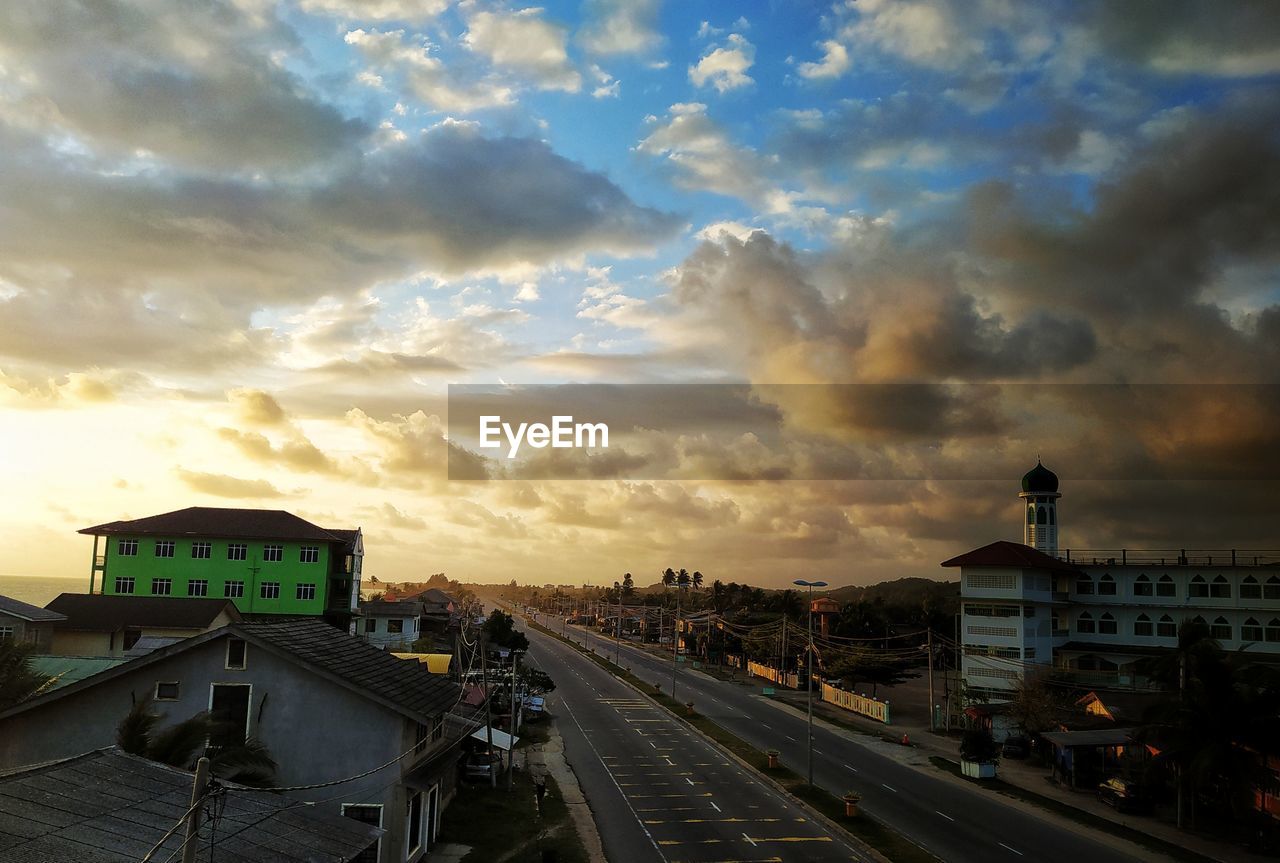 Cars on road in city against sky during sunrise