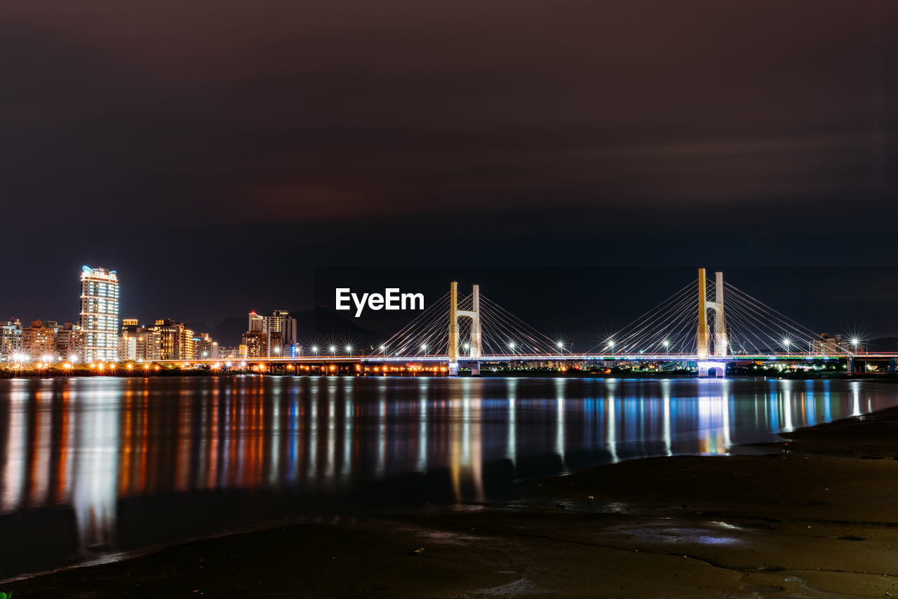 Illuminated bridge over river at night