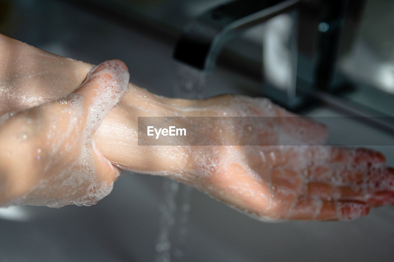 CLOSE-UP OF HAND PREPARING FOOD IN WATER AT HOME
