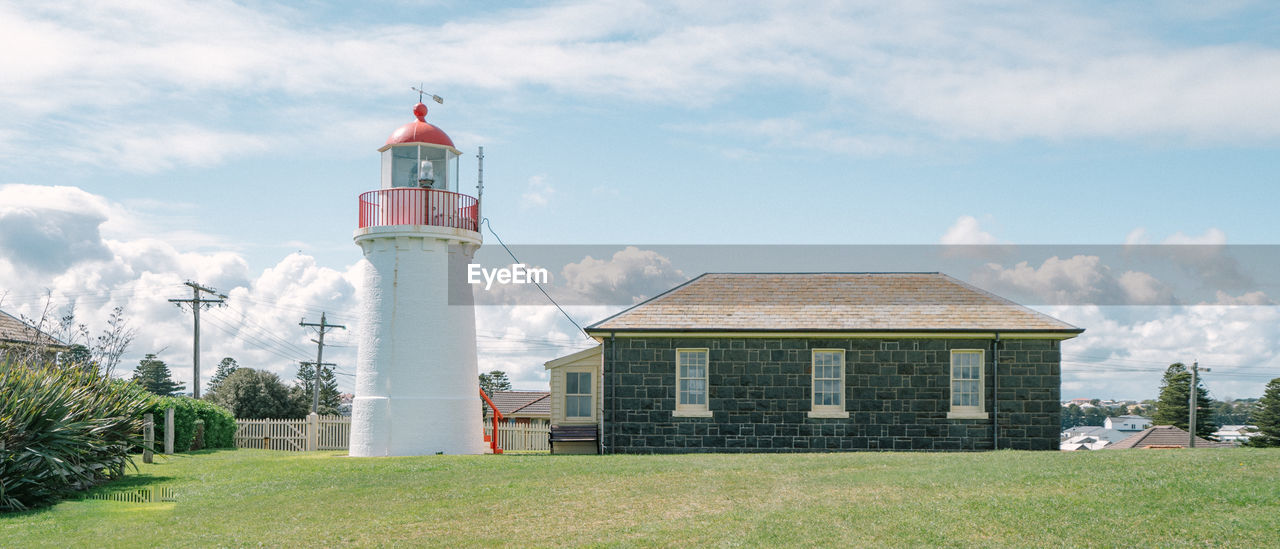 LIGHTHOUSE AGAINST BUILDINGS AND SKY