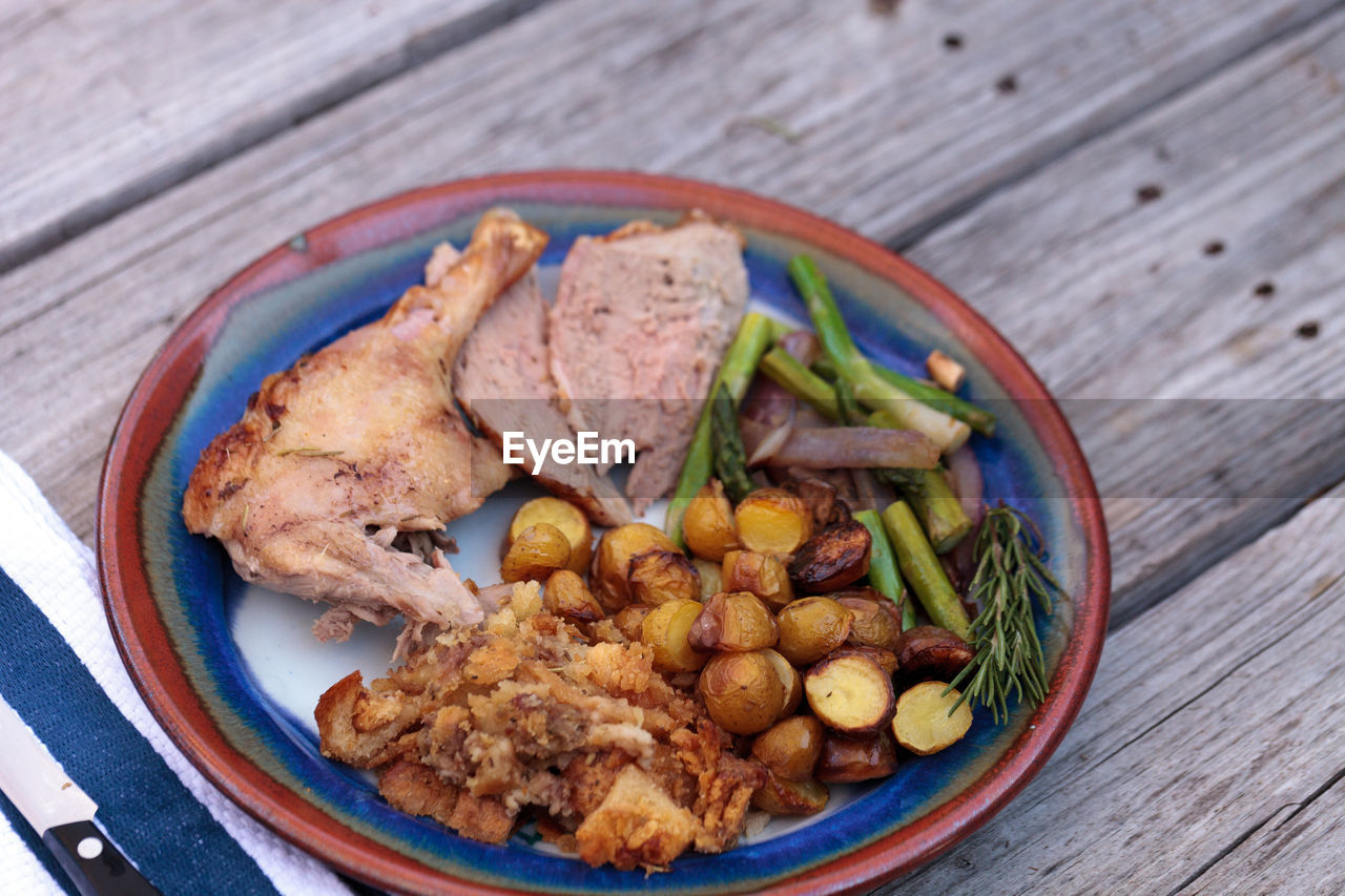 High angle view of roast chicken with vegetables served in plate on wooden table