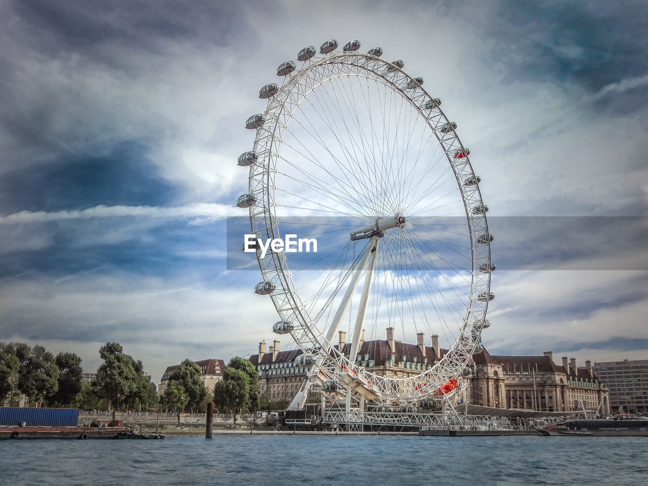 London eye by river against cloudy sky