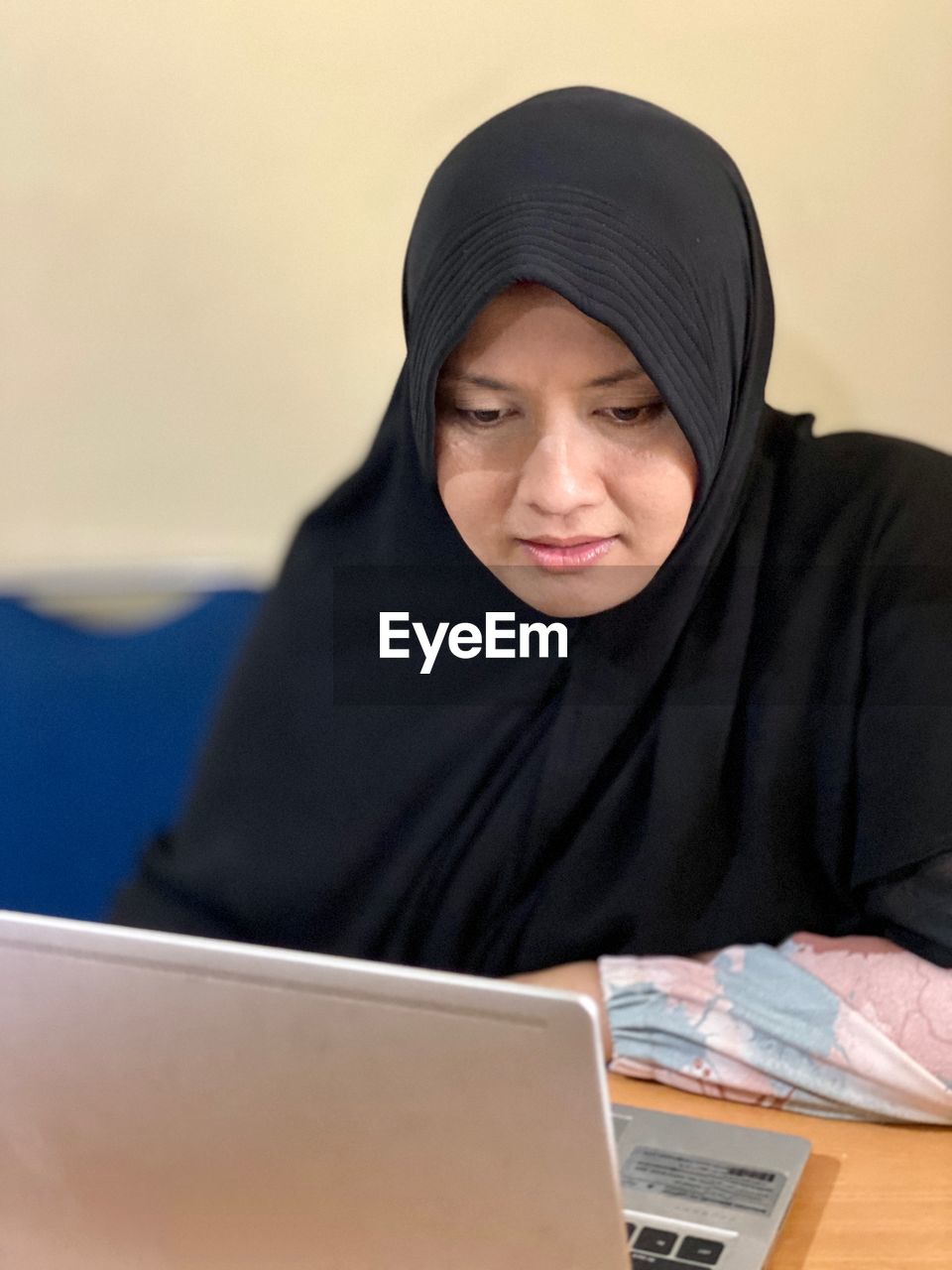 MID ADULT WOMAN USING MOBILE PHONE IN LAPTOP