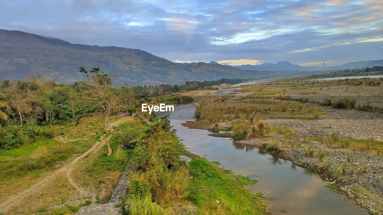 Scenic view of river by mountains against sky