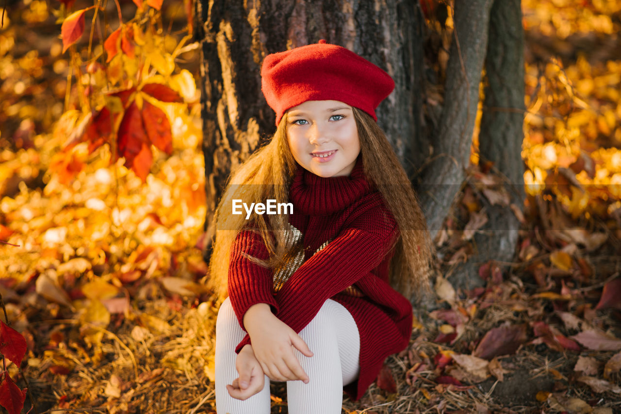 Cute baby girl with long hair in autumn in the park smiling and enjoying a sunny day