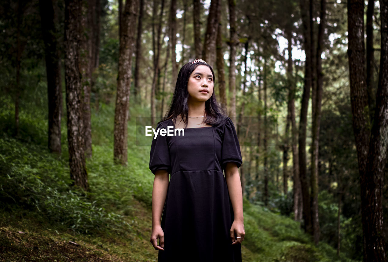 Portrait of young woman standing in forest