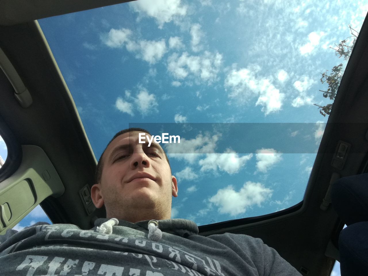 LOW ANGLE VIEW OF MAN SITTING IN CAR