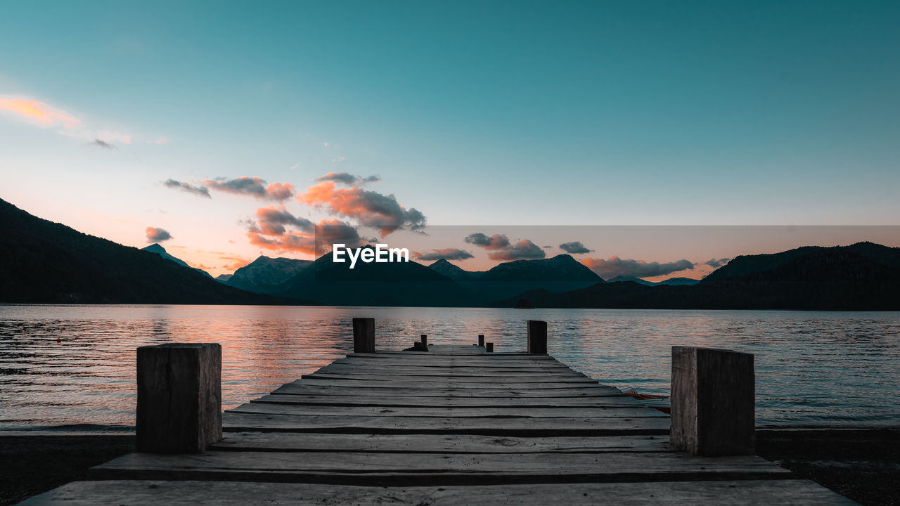 Pier over lake against sky during sunset