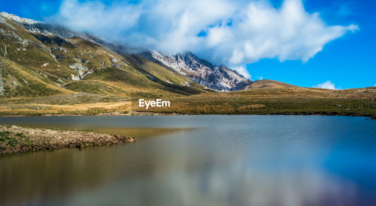 Scenic view of lake by mountains against sky