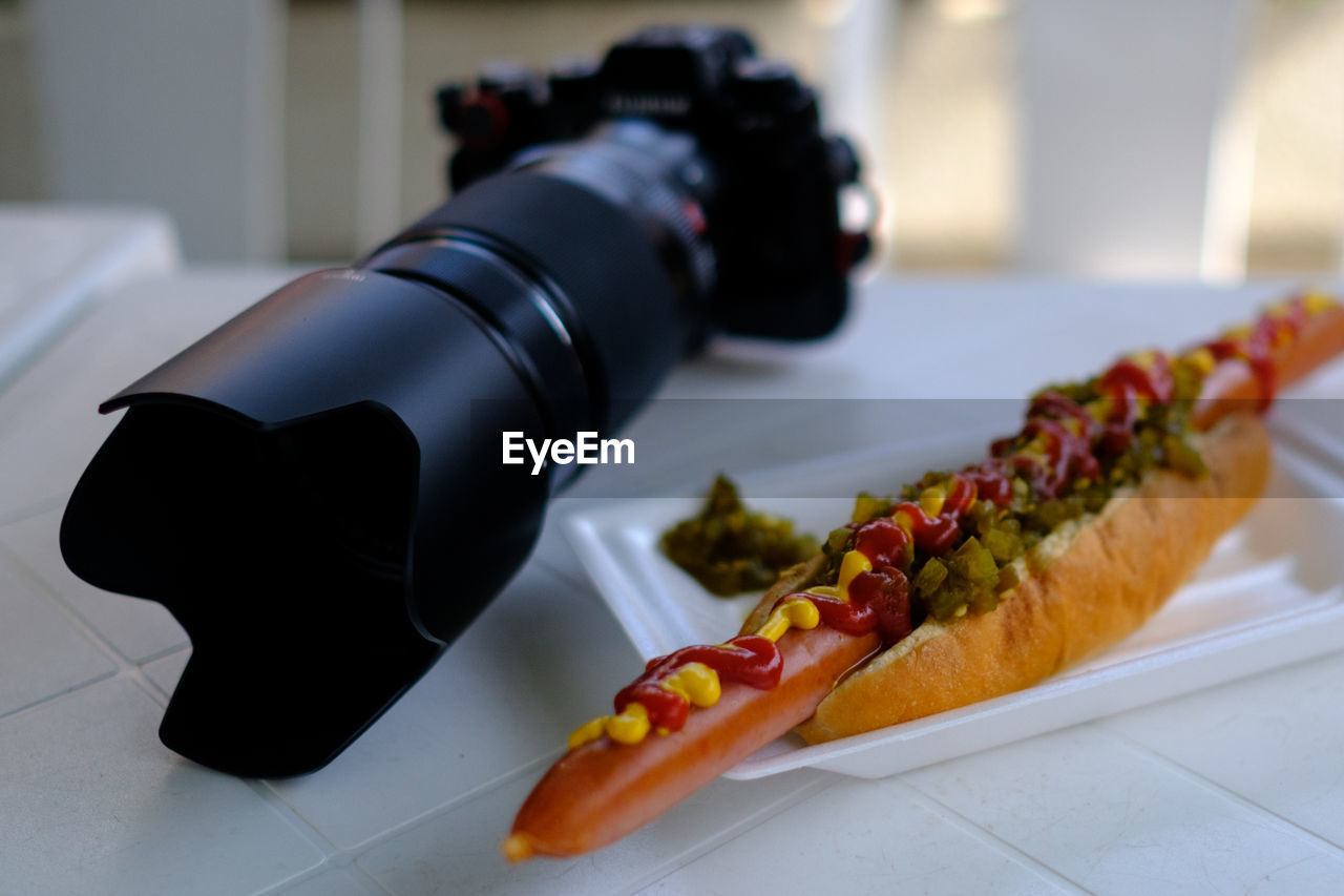 Close-up of hot dog and camera on table