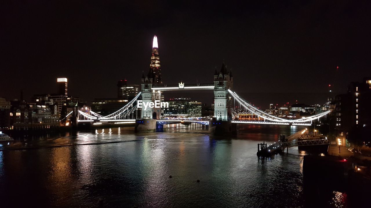 Illuminated tower bridge over river at night