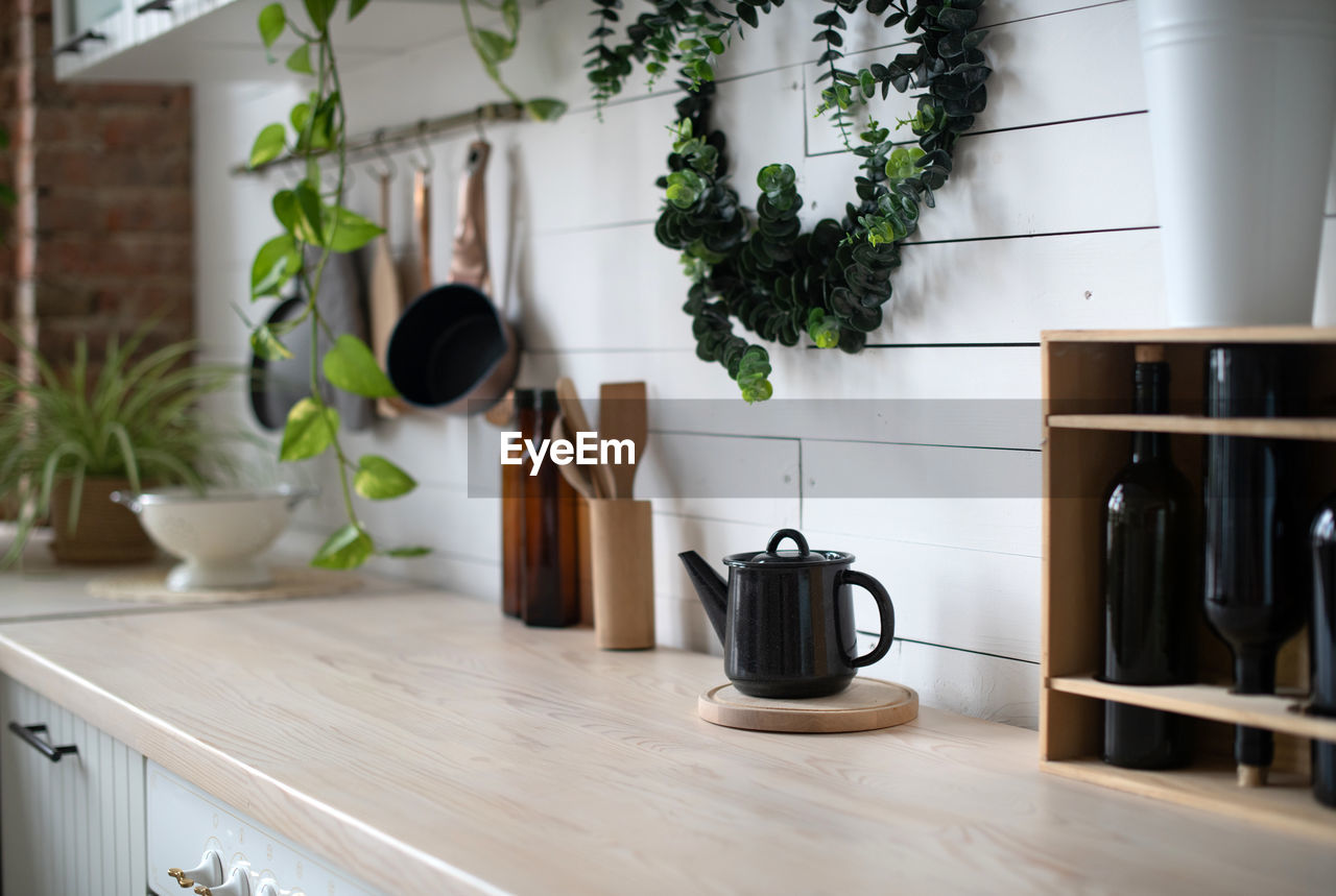 A black kettle and potted plant on table at kitchen 