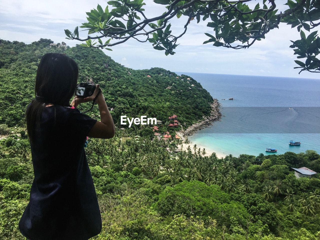 REAR VIEW OF WOMAN PHOTOGRAPHING ON SEA