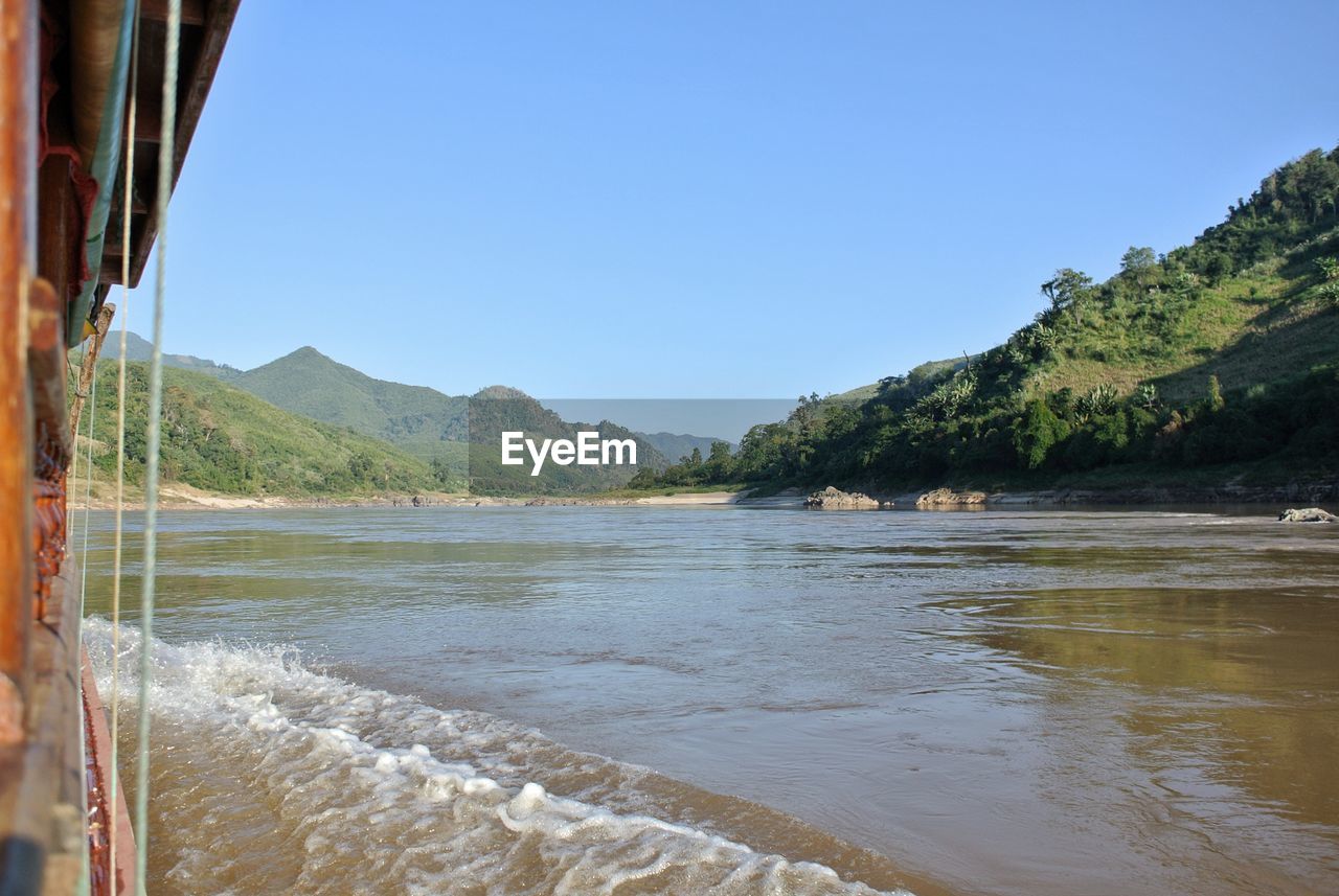 SCENIC VIEW OF SEA BY MOUNTAINS AGAINST CLEAR SKY