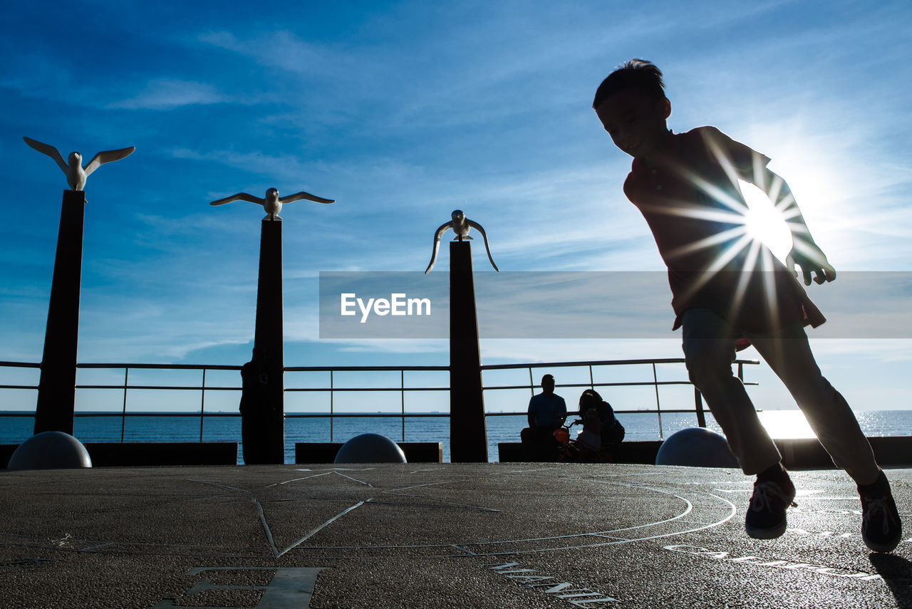 Playful boy at promenade against sky