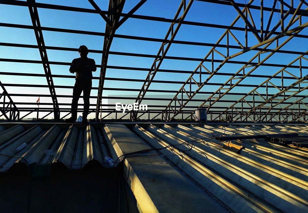 Man standing below metallic roof