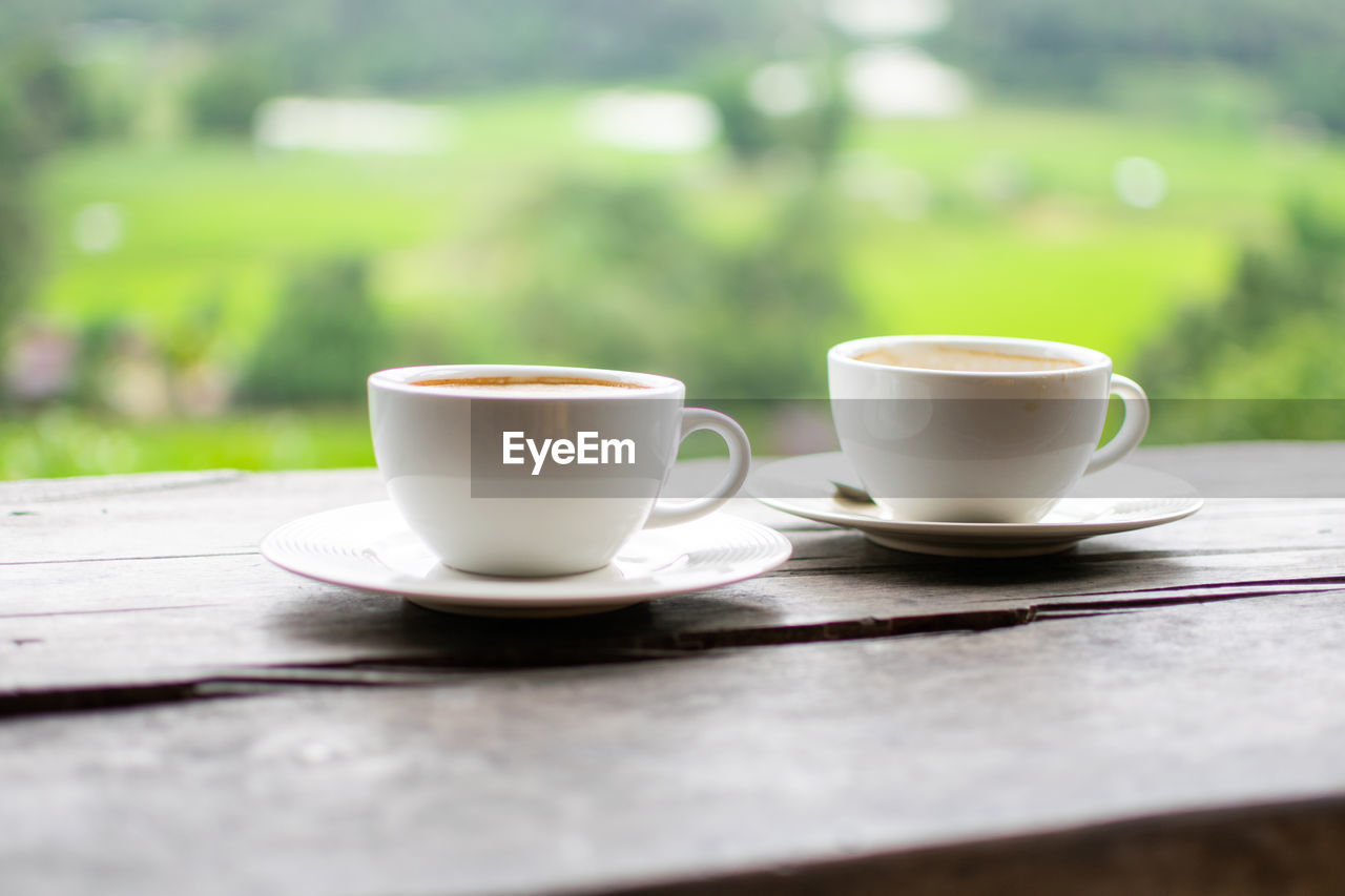 mug, cup, drink, food and drink, coffee, coffee cup, crockery, refreshment, hot drink, saucer, table, wood, selective focus, relaxation, tea cup, morning, tea, no people, day, nature, coffee break, cafe, outdoors, food, focus on foreground, freshness, copy space, heat, tableware, ceramic, lifestyles, still life, close-up, spoon, plant, porcelain