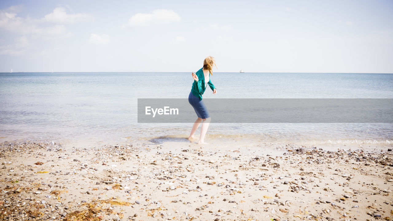 Full length of a woman standing on beach against sky
