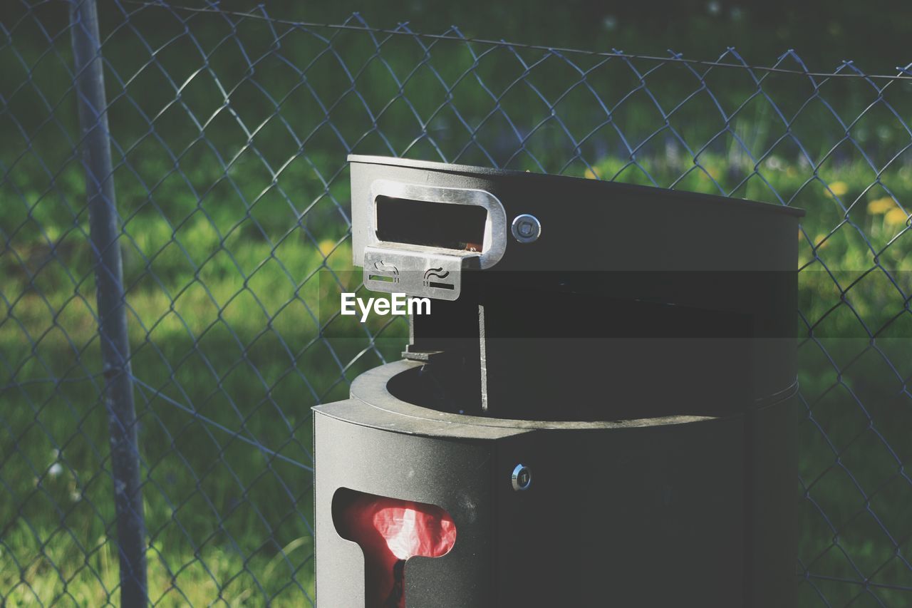 Close-up of dustbin against chainlink fence