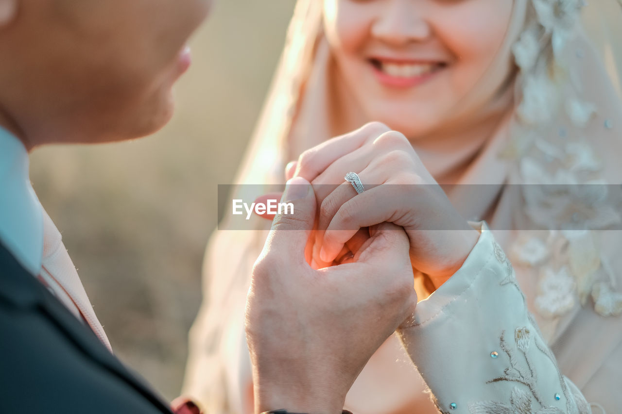 Midsection of couple holding hands during wedding ceremony