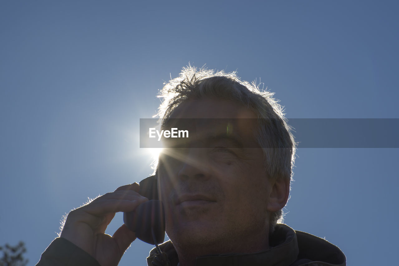 Low angle portrait of man against clear sky