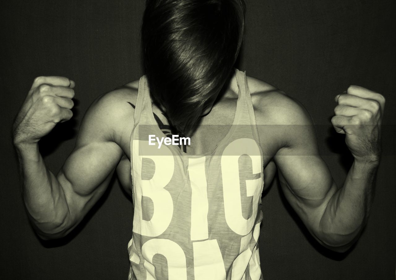 Young muscular man flexing muscles by wall