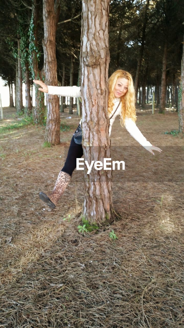 MAN STANDING ON TREE TRUNK IN PARK