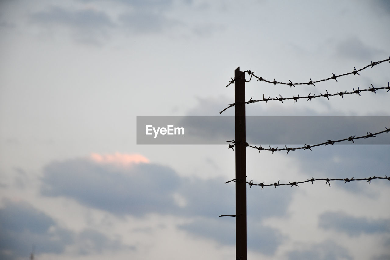 sky, cloud, protection, wire, security, barbed wire, overhead power line, fence, electricity, nature, metal, no people, sign, communication, warning sign, technology, wire fencing, outdoors, outdoor structure, low angle view, day, forbidden, architecture, line, wind, blue, security system, cable