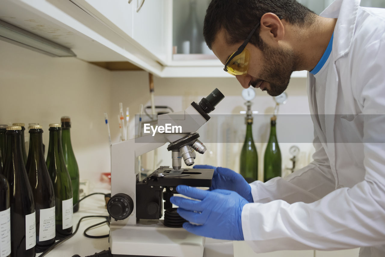 Winemaker analyzing a sample under a microscope in a winery lab.