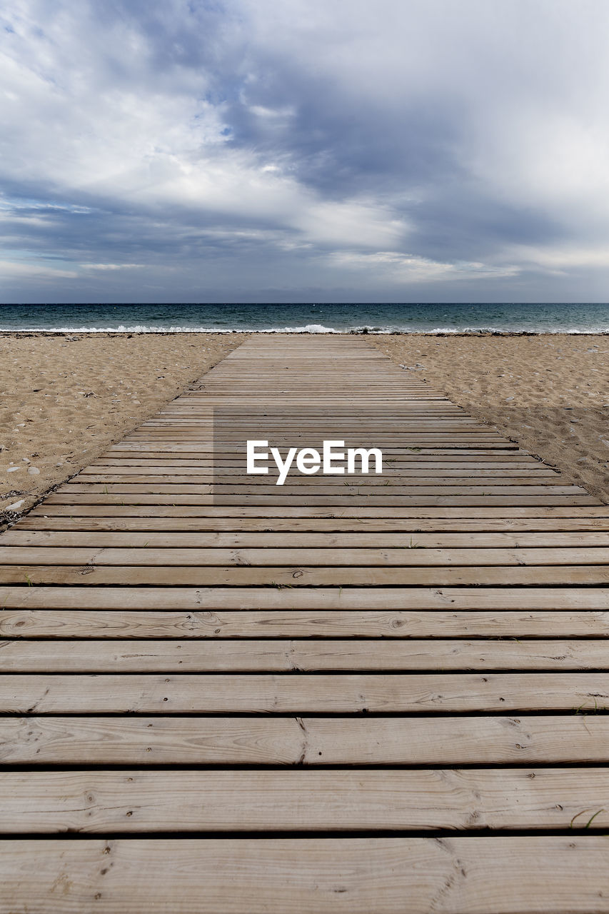 Boardwalk leading towards sea against sky