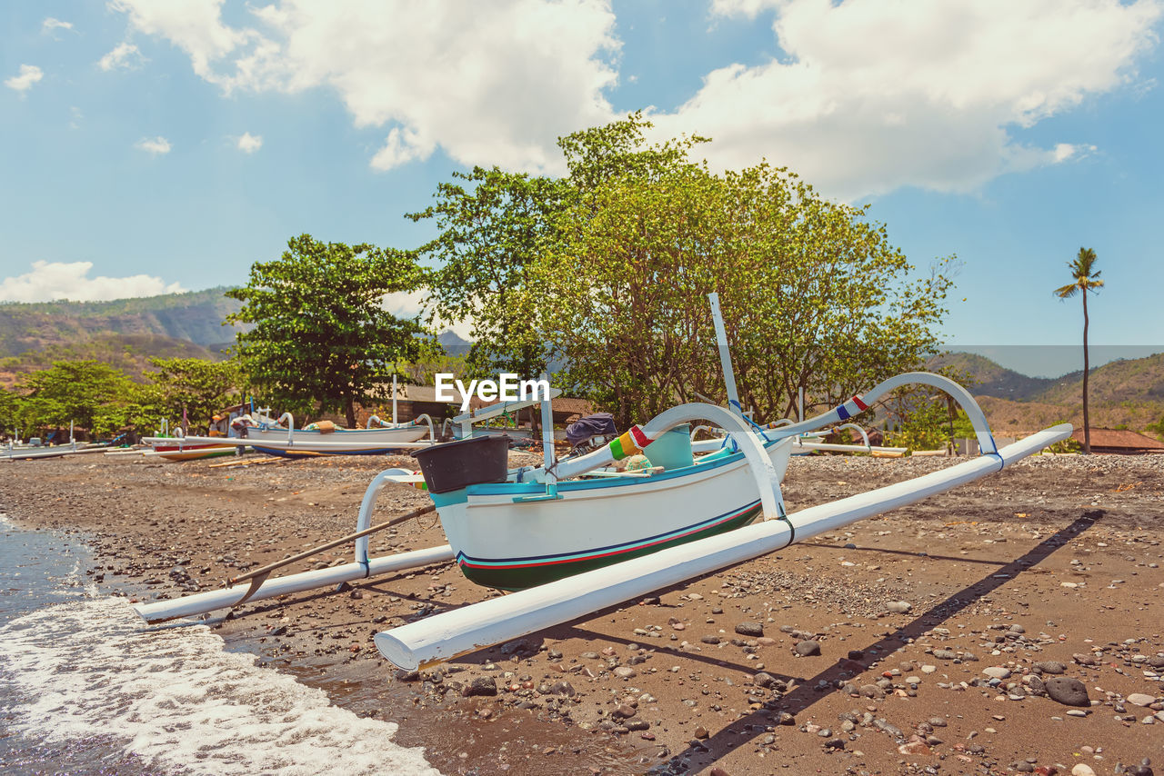 BOATS MOORED ON SHORE AGAINST SKY