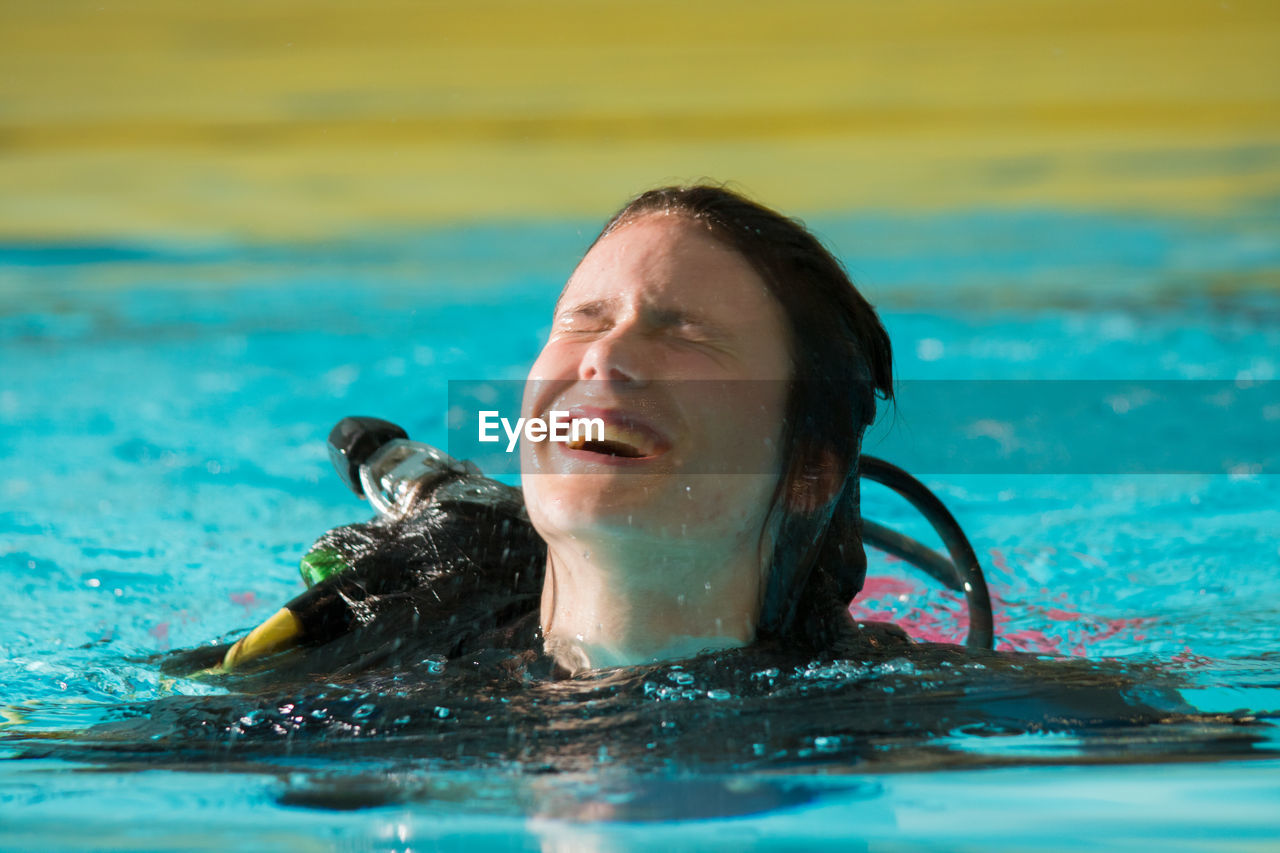 Close-up of cheerful young woman swimming in pool