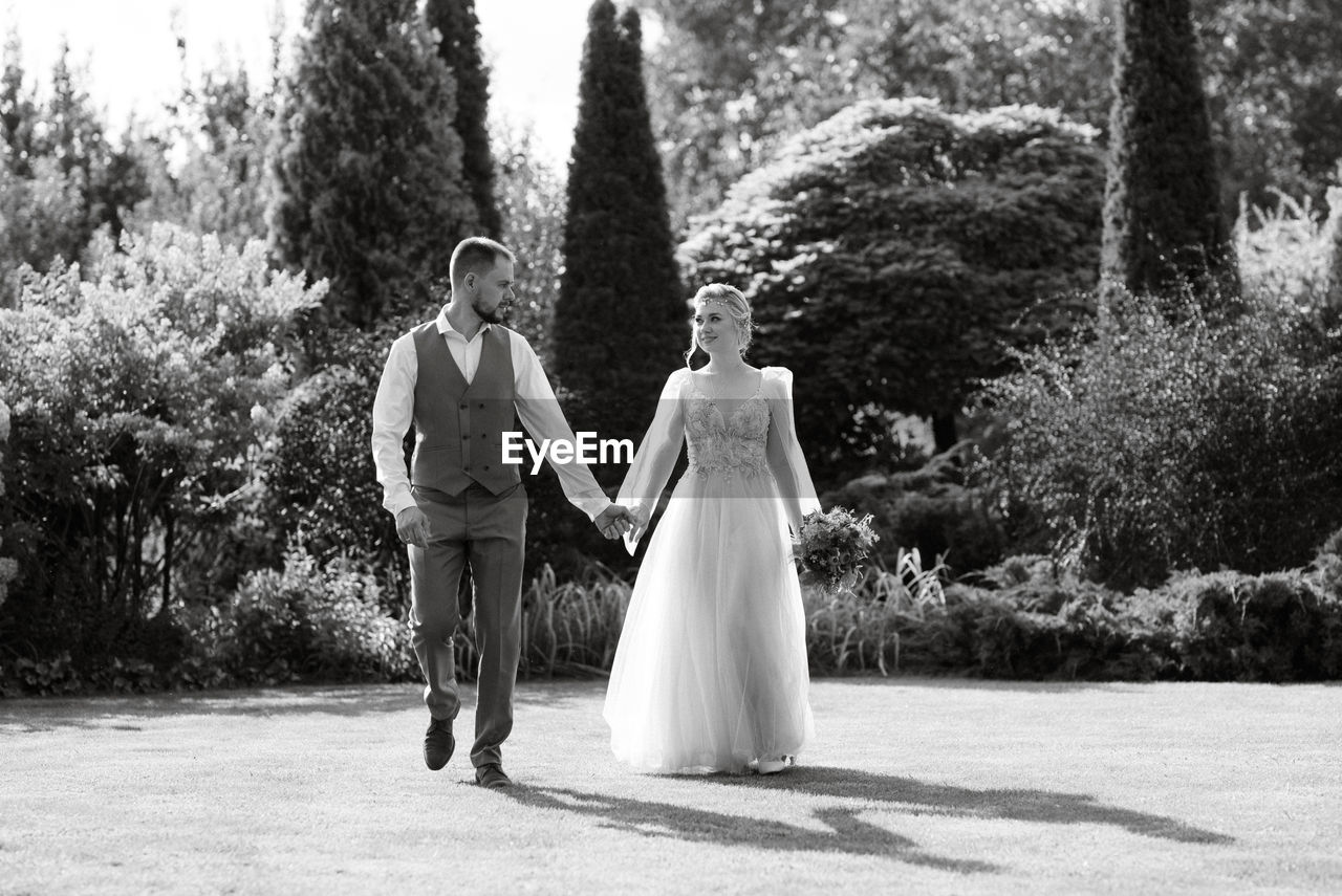 wedding, adult, women, bride, newlywed, event, celebration, love, wedding dress, full length, black and white, plant, tree, life events, married, two people, men, togetherness, positive emotion, nature, emotion, female, young adult, day, standing, monochrome photography, ceremony, formal wear, monochrome, gown, rear view, happiness, dress, clothing, outdoors, bonding, beginnings, romance, sunlight, lifestyles, bridal clothing, person, walking, fashion, bouquet, flower