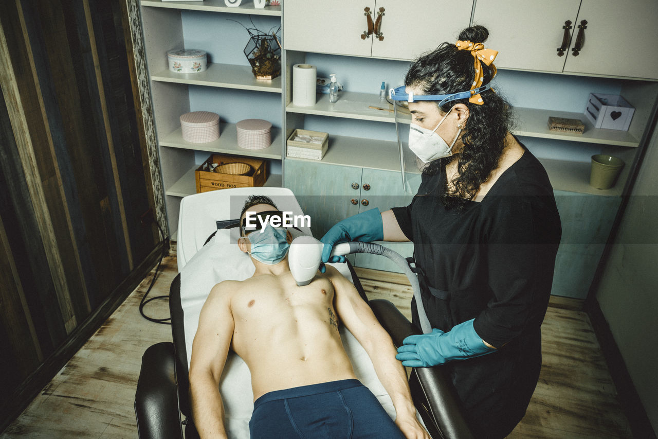 Beautician working with mask and protective screen for the virus covid