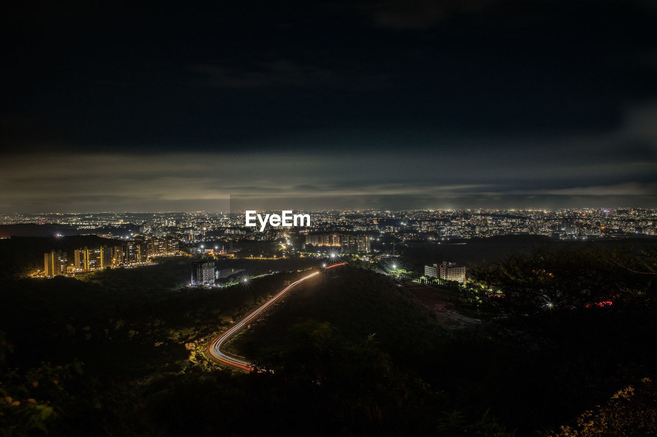 HIGH ANGLE VIEW OF ILLUMINATED BUILDINGS IN CITY AGAINST SKY