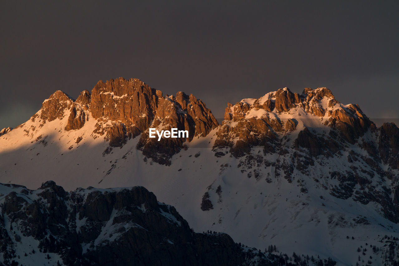 Low angle view of snowcapped mountains against sky