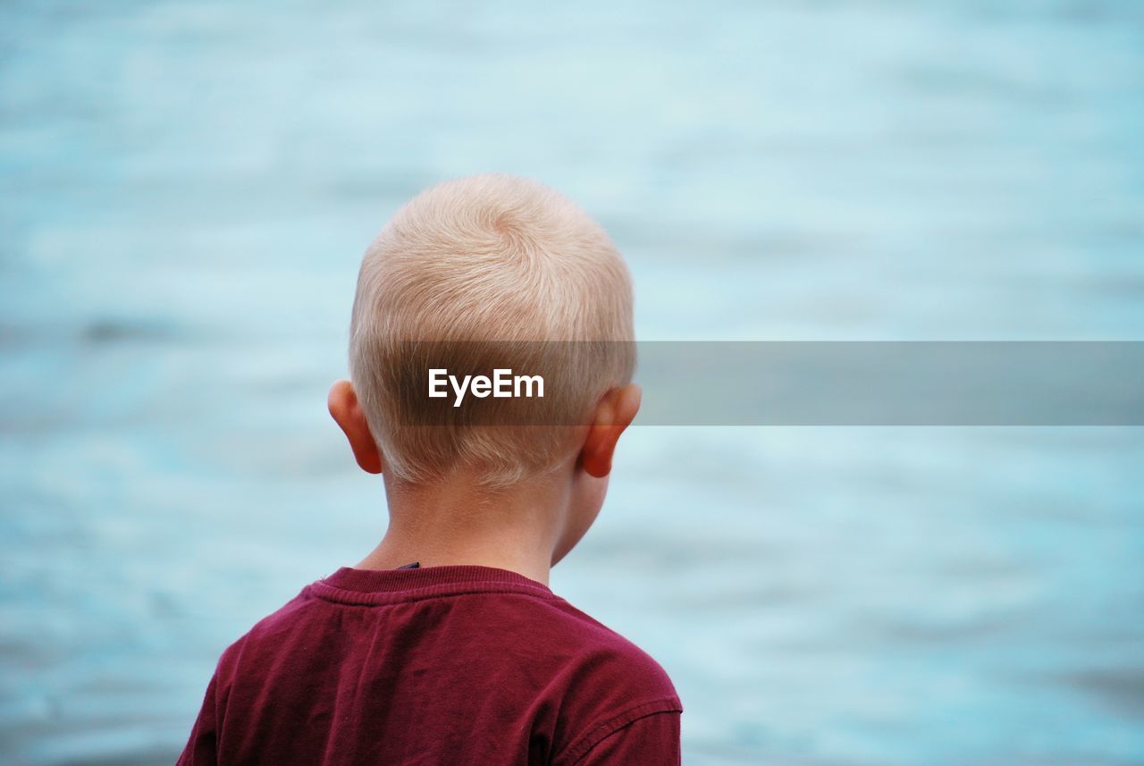 Rear view of boy standing against sea