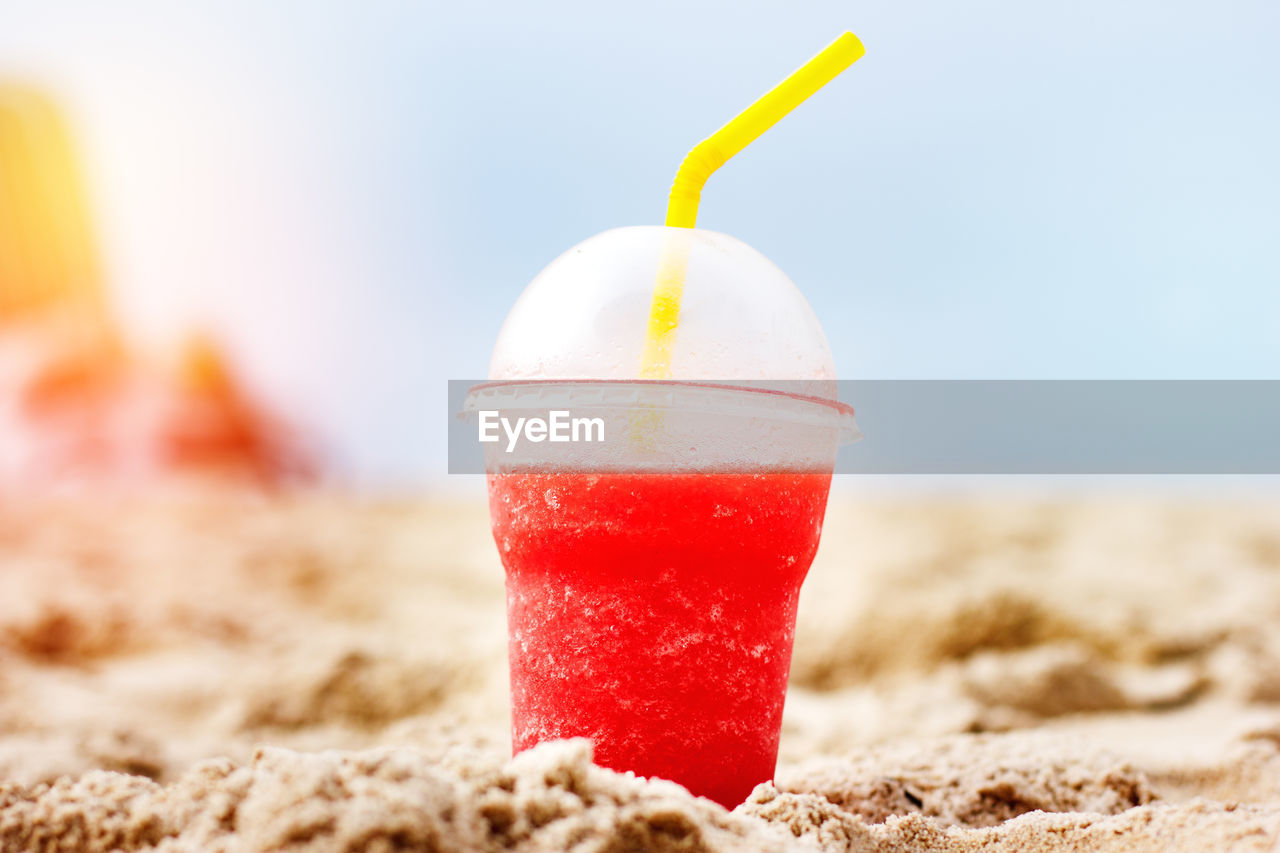 CLOSE-UP OF DRINK IN GLASS ON BEACH
