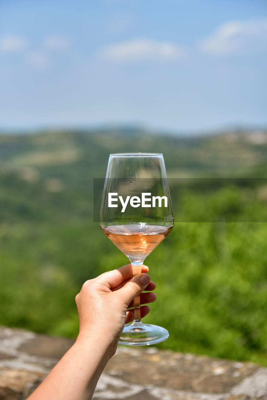 Selective focus personal perspective photo of woman holding glass of rose wine