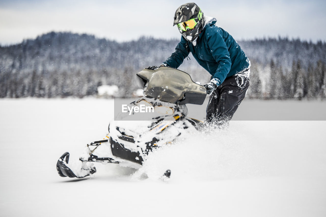 Confident and aggressive rider operates snowmobile in deep snow.