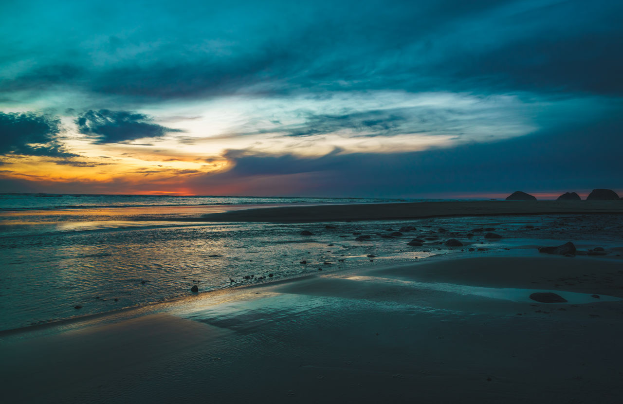 Scenic view of beach against dramatic sky during sunset