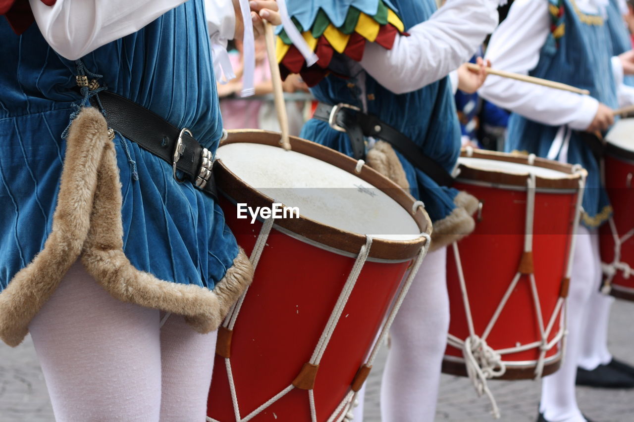 Midsection of people playing drums