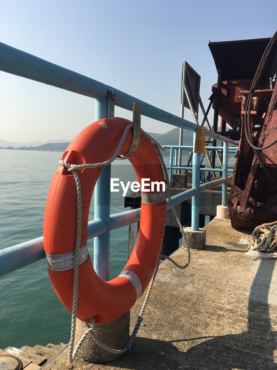 CLOSE-UP OF CLOTHES HANGING BY RAILING AGAINST SEA