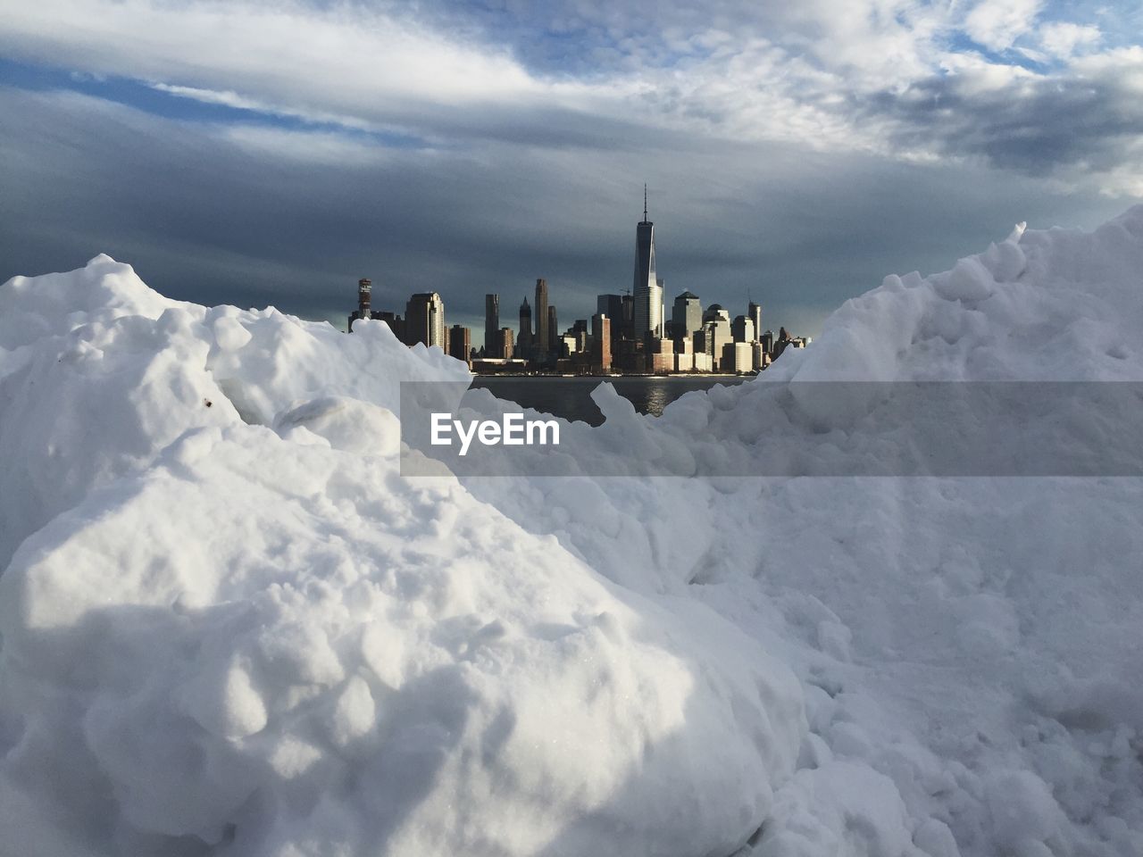 One world trade center amidst buildings in front of snow during sunny day