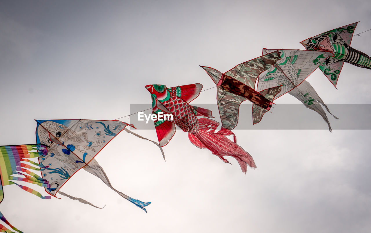 Low angle view of kites flying in sky